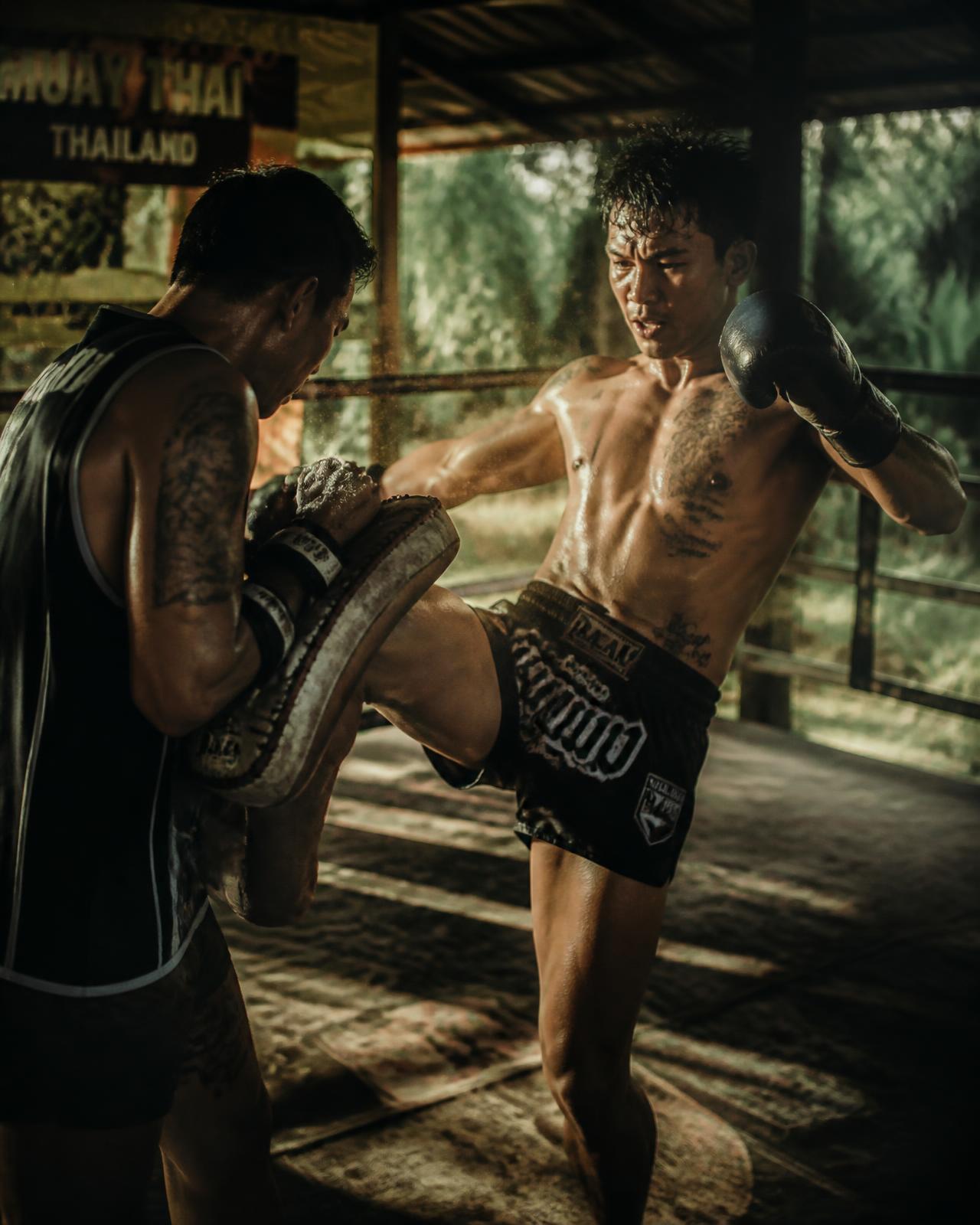 Muay Thai fighter training on pads at an open-air camp in Thailand